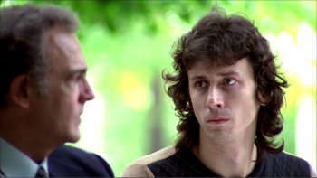 Movie still from “Cruising” (1980), directed by William Friedkin – A man with long curly hair is looking at another man; Close Up shot, Low angle