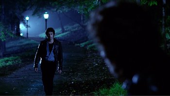 Movie still from “Cruising” (1980), directed by William Friedkin – A man walking down a path in the dark; Wide shot, Over the shoulder angle