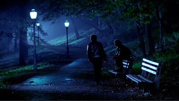Movie still from “Cruising” (1980), directed by William Friedkin – Two people are walking on a path at night; Wide shot, Over the shoulder angle