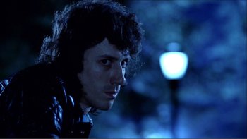 Movie still from “Cruising” (1980), directed by William Friedkin – A man with curly black hair wearing headphones; Close Up shot, Low angle