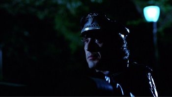 Movie still from “Cruising” (1980), directed by William Friedkin – A man in a police uniform is standing in the dark; Close Up shot, Low angle