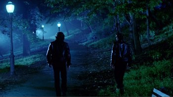 Movie still from “Cruising” (1980), directed by William Friedkin – Two people walking down a dark path at night; Wide shot, Low angle