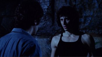 Movie still from “Cruising” (1980), directed by William Friedkin – A man and a woman standing next to each other in the dark; Medium shot, Over the shoulder angle
