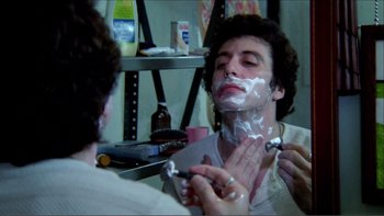 Movie still from “Cruising” (1980), directed by William Friedkin – A man is shaving his face in a barber shop; Close Up shot, Over the shoulder angle