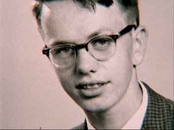 Movie still from “Crumb” (1994), directed by Terry Zwigoff – An old photo of a young man wearing glasses; Extreme Close Up shot, Overhead angle