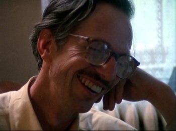 Movie still from “Crumb” (1994), directed by Terry Zwigoff – A man wearing glasses and smiling for the camera; Close Up shot, Low angle