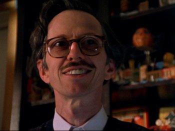 Movie still from “Crumb” (1994), directed by Terry Zwigoff – A person wearing glasses and a suit; Close Up shot, Low angle