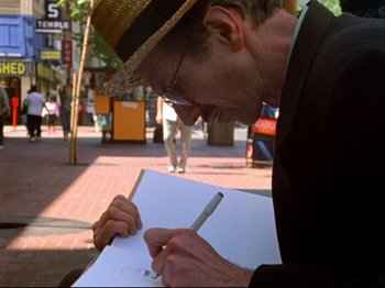 Movie still from “Crumb” (1994), directed by Terry Zwigoff – A man wearing a straw hat writing on a piece of paper; Close Up shot, Low angle