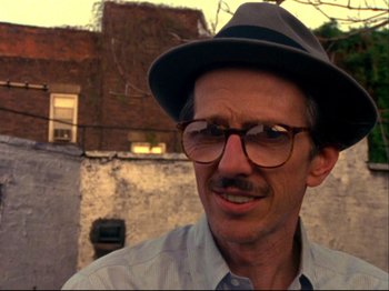 Movie still from “Crumb” (1994), directed by Terry Zwigoff – A person wearing glasses and a hat; Close Up shot, Low angle