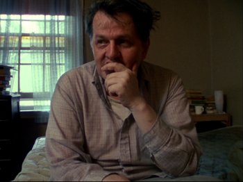 Movie still from “Crumb” (1994), directed by Terry Zwigoff – A man sitting at a table with his hand under his chin; Close Up shot, Low angle