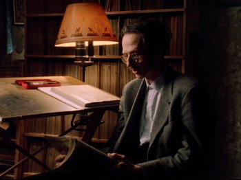 Movie still from “Crumb” (1994), directed by Terry Zwigoff – A man sitting at a table reading a newspaper; Medium shot, High angle