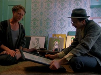 Movie still from “Crumb” (1994), directed by Terry Zwigoff – Two men sitting on the floor looking at a laptop; Medium shot, Over the shoulder angle
