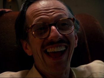 Movie still from “Crumb” (1994), directed by Terry Zwigoff – An older man wearing glasses and smiling for the camera; Close Up shot, Low angle
