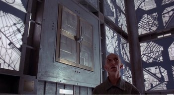 Movie still from “Cube” (1997), directed by Vincenzo Natali – A man standing in front of an open window; Medium shot, Low angle