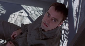 Movie still from “Cube” (1997), directed by Vincenzo Natali – A person sitting on a chair; Close Up shot, Overhead angle