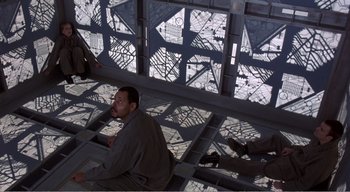 Movie still from “Cube” (1997), directed by Vincenzo Natali – A man sitting on the floor of a building; Wide shot, Overhead angle