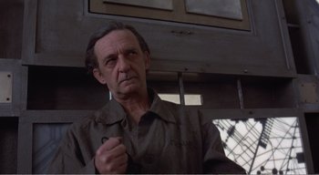 Movie still from “Cube” (1997), directed by Vincenzo Natali – An older man in a brown shirt is looking at the camera; Close Up shot, Low angle