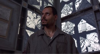 Movie still from “Cube” (1997), directed by Vincenzo Natali – A man in a gray jacket looking up at the ceiling; Close Up shot, Low angle