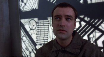 Movie still from “Cube” (1997), directed by Vincenzo Natali – A person looking at the camera; Close Up shot, Low angle