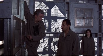 Movie still from “Cube” (1997), directed by Vincenzo Natali – Two men are standing next to each other; Medium shot, Low angle
