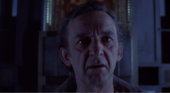 Movie still from “Cube” (1997), directed by Vincenzo Natali – An older man with a serious look on his face; Close Up shot, Low angle
