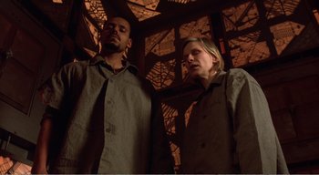 Movie still from “Cube” (1997), directed by Vincenzo Natali – A man and a woman standing next to each other; Medium shot, Low angle