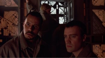 Movie still from “Cube” (1997), directed by Vincenzo Natali – Two men sitting next to each other in a room; Close Up shot, Low angle
