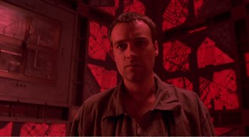 Movie still from “Cube” (1997), directed by Vincenzo Natali – A man standing in front of a red wall; Close Up shot, Low angle
