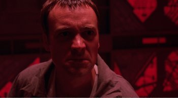 Movie still from “Cube” (1997), directed by Vincenzo Natali – A person in a dark room; Close Up shot, Over the shoulder angle