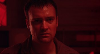 Movie still from “Cube” (1997), directed by Vincenzo Natali – A person in a dark room; Close Up shot, Low angle