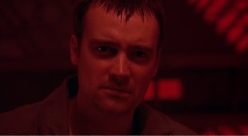 Movie still from “Cube” (1997), directed by Vincenzo Natali – A person in a dark room; Close Up shot, Low angle