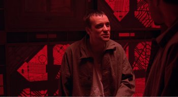 Movie still from “Cube” (1997), directed by Vincenzo Natali – A man standing in front of a red wall; Medium shot, Low angle