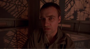 Movie still from “Cube” (1997), directed by Vincenzo Natali – A person in a dark room; Close Up shot, Low angle