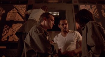 Movie still from “Cube” (1997), directed by Vincenzo Natali – Two men sitting in a room talking to each other; Medium shot, High angle