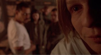 Movie still from “Cube” (1997), directed by Vincenzo Natali – A person's face with other people in the background; Close Up shot, Low angle