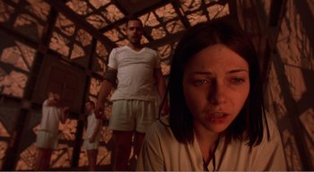 Movie still from “Cube” (1997), directed by Vincenzo Natali – A man and a woman standing next to each other in a room; Medium shot, Low angle