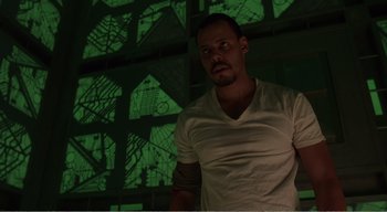 Movie still from “Cube” (1997), directed by Vincenzo Natali – A man standing in front of a wall with green lights on it; Medium shot, Low angle