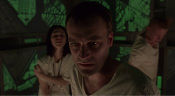 Movie still from “Cube” (1997), directed by Vincenzo Natali – A man and a woman in a room with green lights; Close Up shot, Low angle