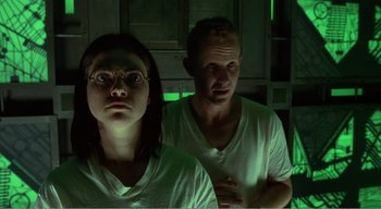 Movie still from “Cube” (1997), directed by Vincenzo Natali – A man and a woman are standing in the dark; Medium shot, Low angle