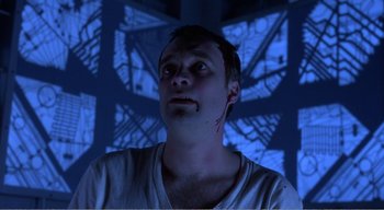 Movie still from “Cube” (1997), directed by Vincenzo Natali – A young man with a white shirt is looking up at the ceiling; Close Up shot, Low angle