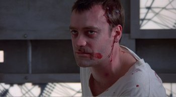 Movie still from “Cube” (1997), directed by Vincenzo Natali – A person with blood on his face; Close Up shot, High angle