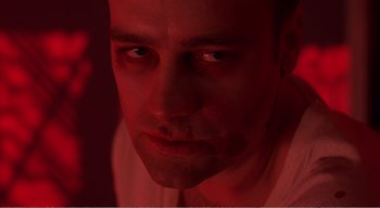 Movie still from “Cube” (1997), directed by Vincenzo Natali – A person in a red light; Close Up shot, Low angle