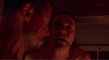 Movie still from “Cube” (1997), directed by Vincenzo Natali – A man looking at another man with blood all over his face; Close Up shot, Low angle