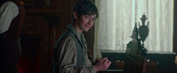 Movie still from “The Greatest Showman” (2017), directed by Michael Gracey – A young man holding a piece of wood in a room; Medium shot, High angle