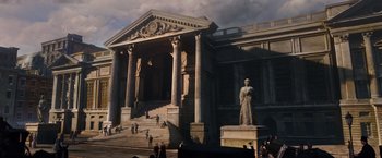 Movie still from “The Greatest Showman” (2017), directed by Michael Gracey – A statue of a man standing in front of a large building; Extreme Wide shot, Low angle