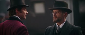 Movie still from “The Greatest Showman” (2017), directed by Michael Gracey – A man in a suit and a man in a hat; Close Up shot, Over the shoulder angle