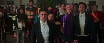 Movie still from “The Greatest Showman” (2017), directed by Michael Gracey – A man in a tuxedo standing in front of a group of people; Medium shot, Over the shoulder angle