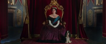 Movie still from “The Greatest Showman” (2017), directed by Michael Gracey – A woman sitting on top of a chair next to a dog; Wide shot, Low angle