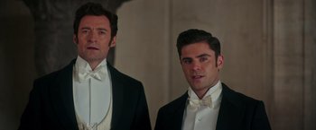 Movie still from “The Greatest Showman” (2017), directed by Michael Gracey – Two men in tuxedos standing next to each other in front of a wall; Close Up shot, Low angle