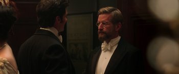 Movie still from “The Greatest Showman” (2017), directed by Michael Gracey – A man in a suit and tie looking at a man in a tuxedo; Medium shot, Over the shoulder angle
